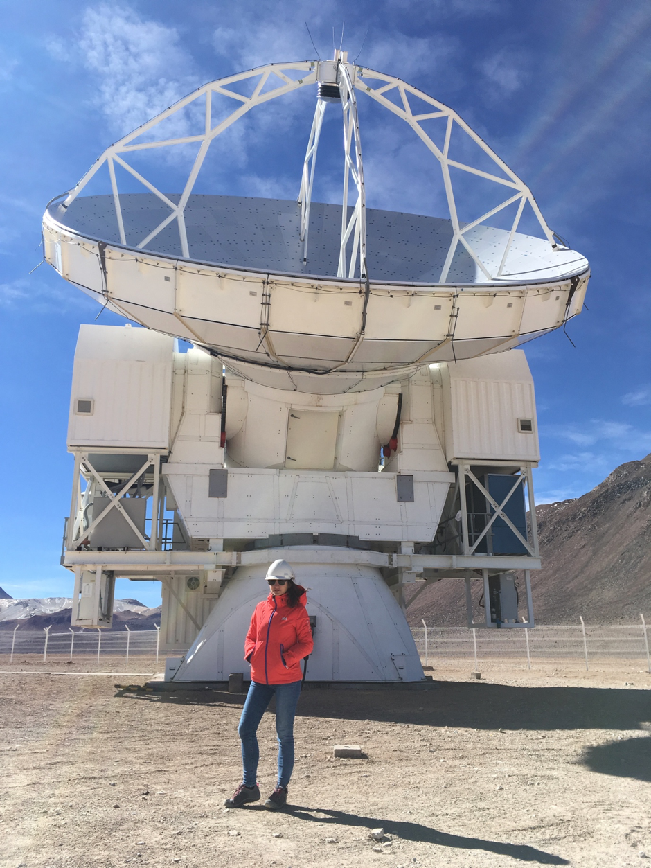 Woman in fornt of a radio telescope in the Atacama desert