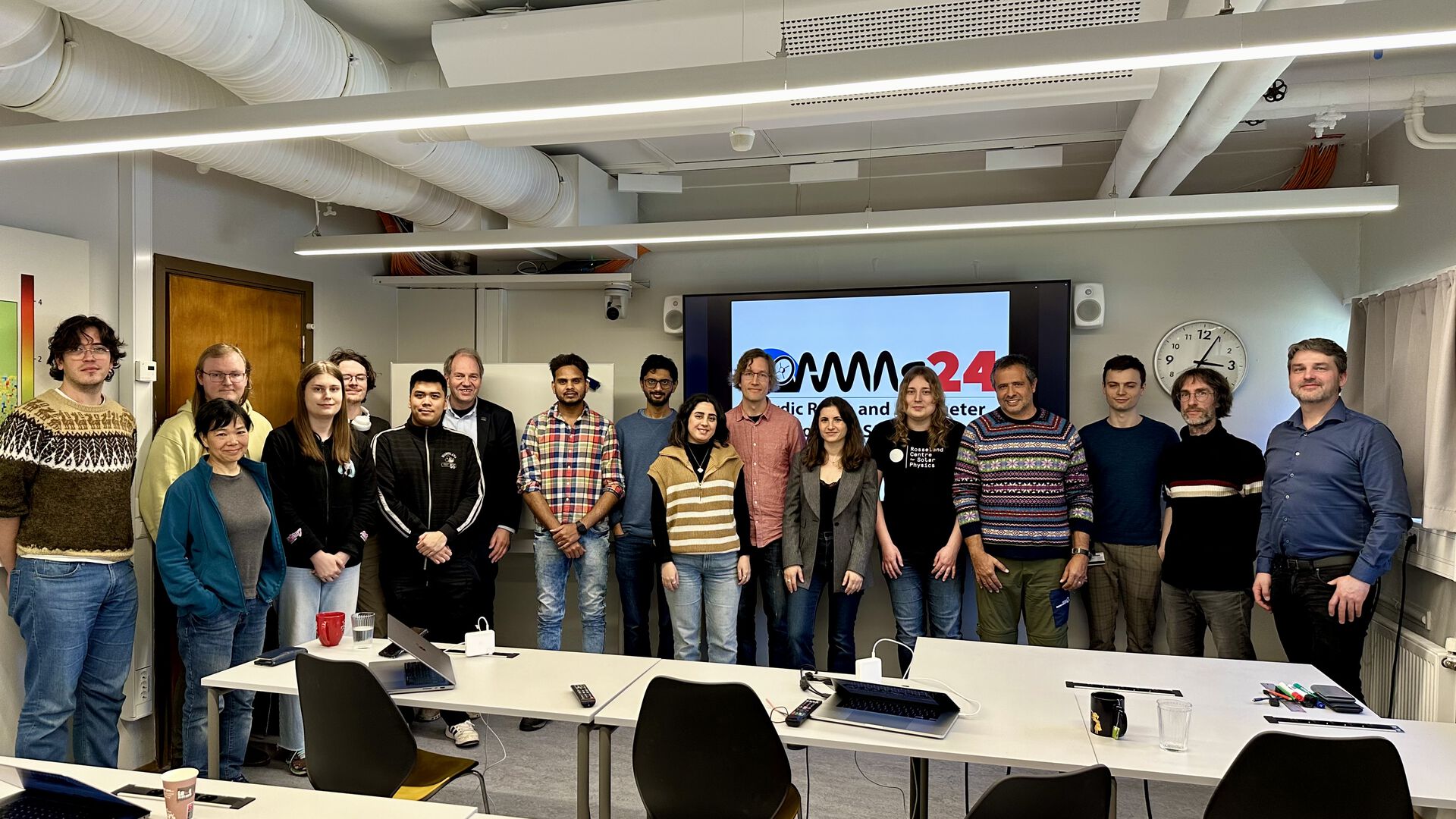 group photo of people standing in a room in from of a screen