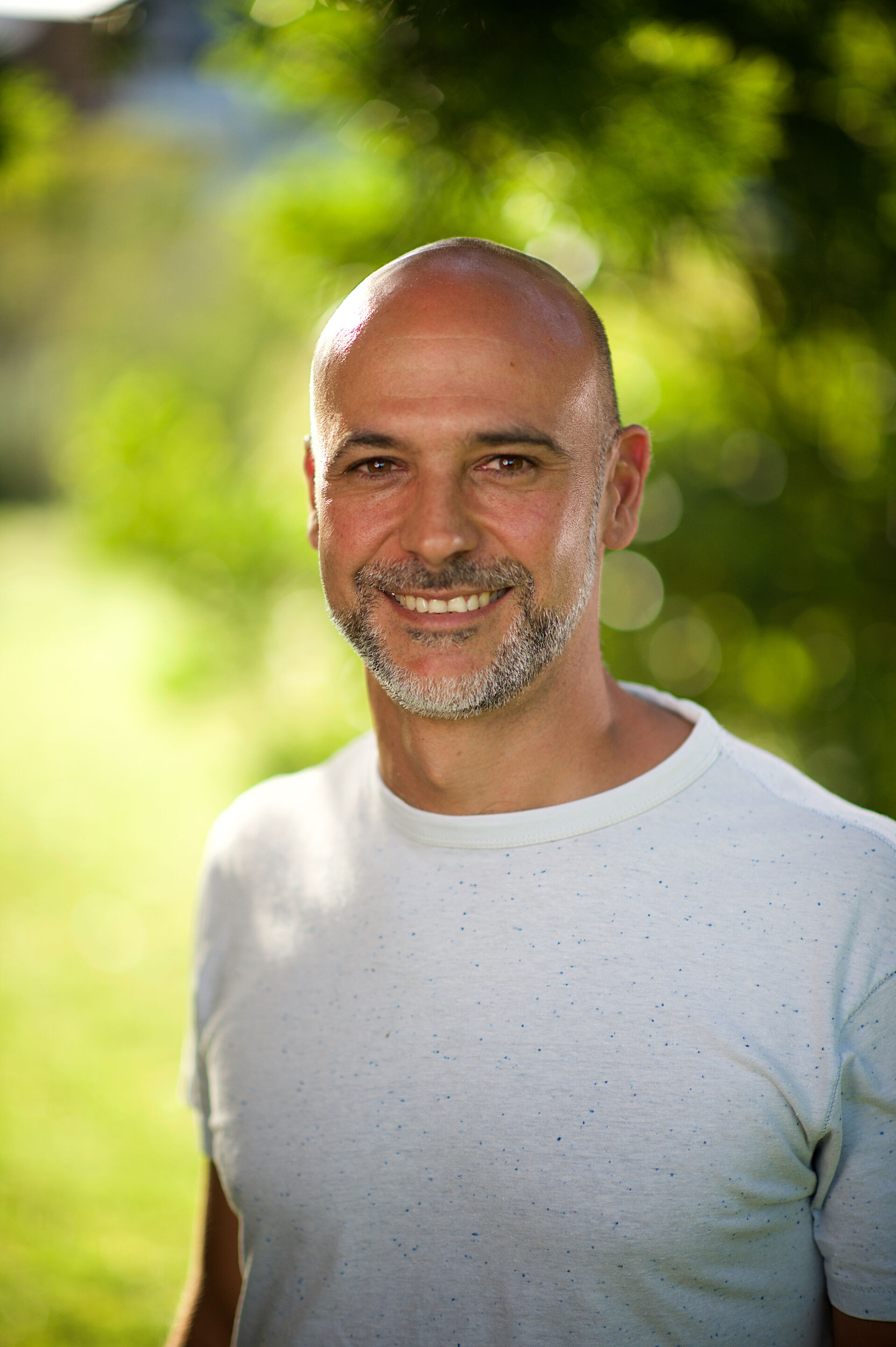 smiling man in front of a green peer tree