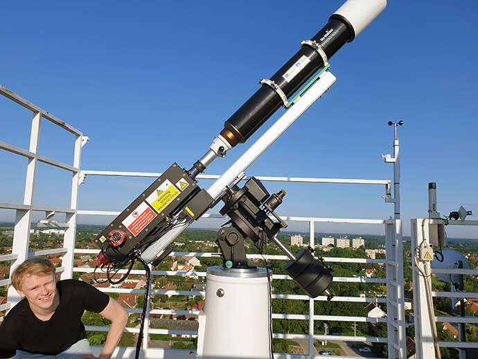 young man next to a telescope