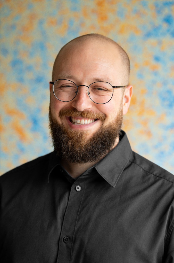 profile photo of a young, smiling man with glasses