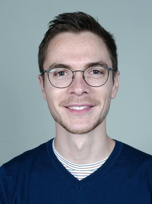 portrettbildet av en smilende, ung mann med briller