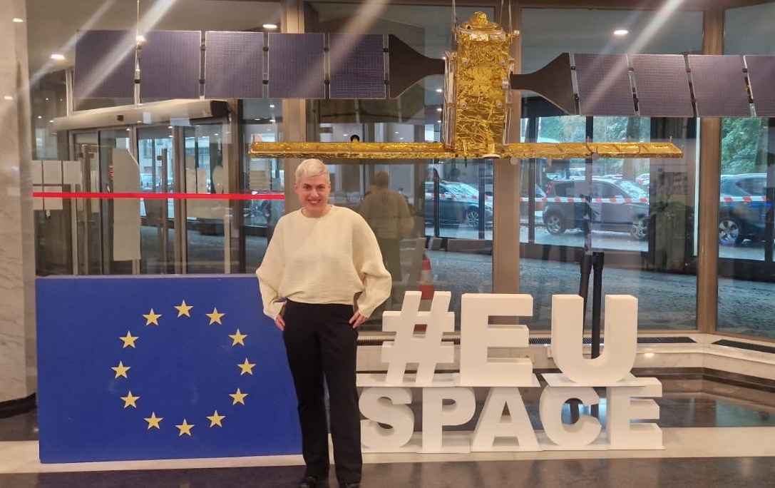 photo of a woman in front of a model satellite