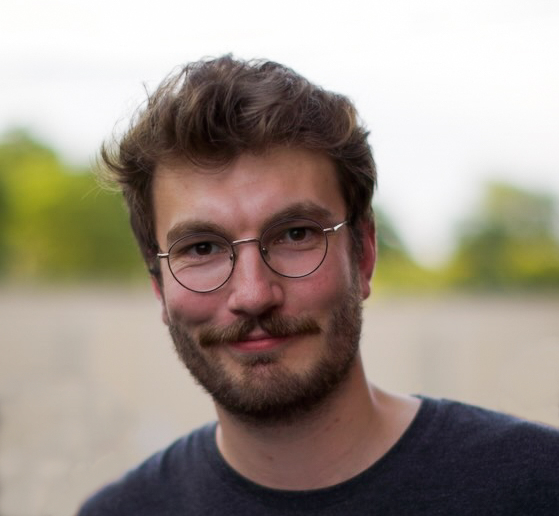 portrettbildet av en ung, smilende mann med briller