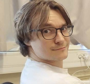 portrettbildet av en smilende, ung mann med briller