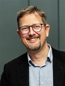 portrettbilde av en smilende man med briller