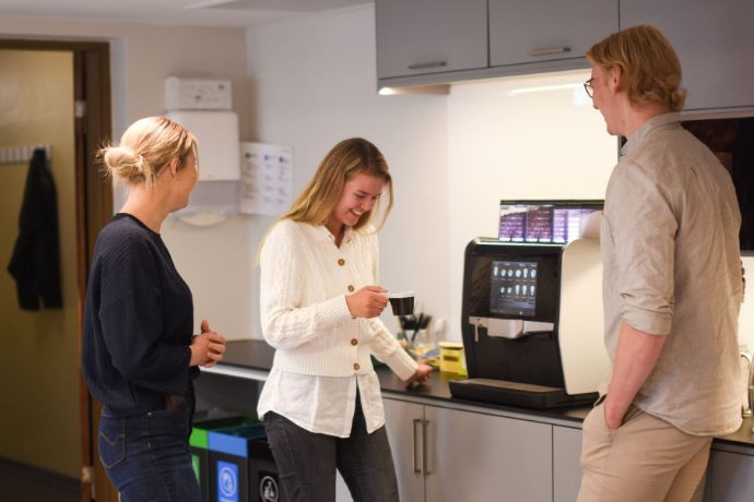 tre studenter som tar pause foran kaffemaskin