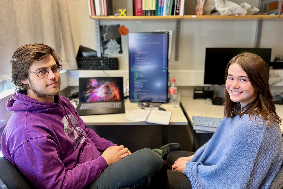 to unge studenter sittende foran PCen og smilende.