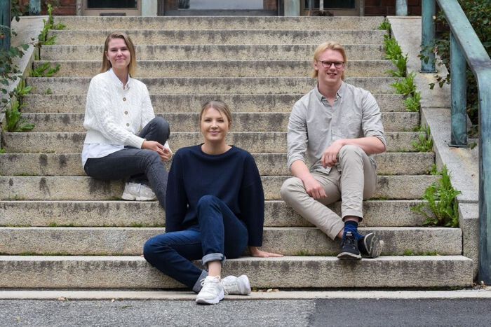 Foto av tre studenter satt på trappa