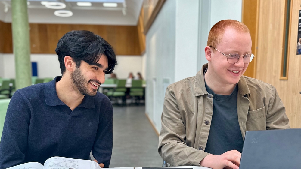 to smilende studenter i lesesalen som ser på en datamaskin