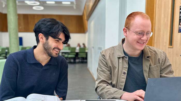 to smilende studenter i lesesalen som ser på en datamaskin