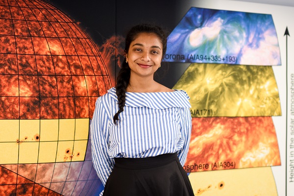 ung kvinnelig astronomi student foran en plakat om sola