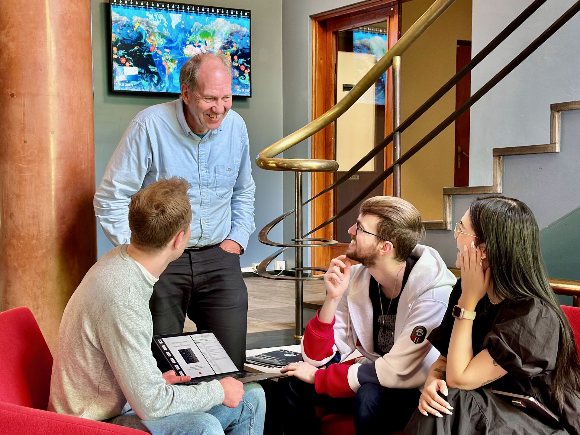 Students smiling and discussing with a professor