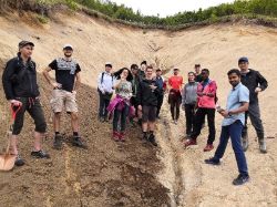 A group of students looking at a sand deposit