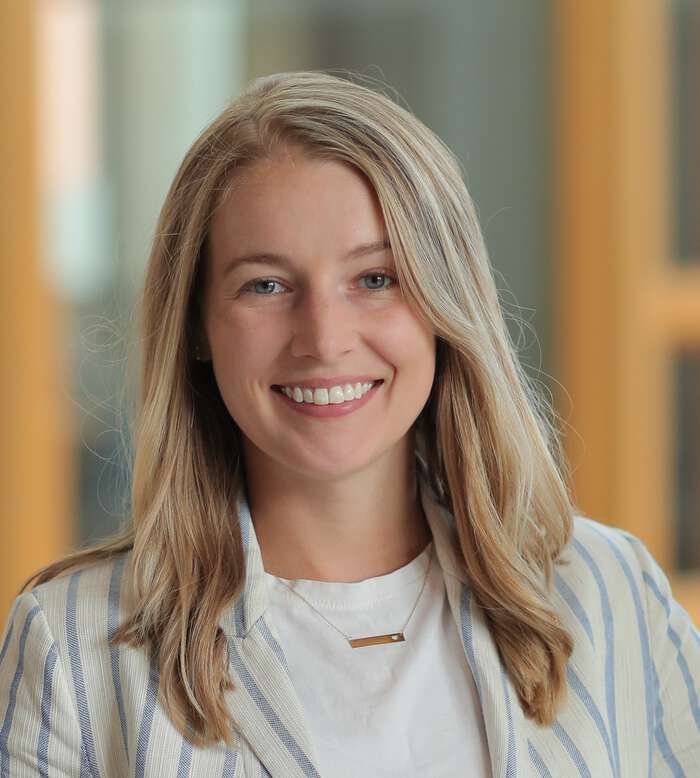 Lizzy Simmons headshot, smiling with white shirt and blazer