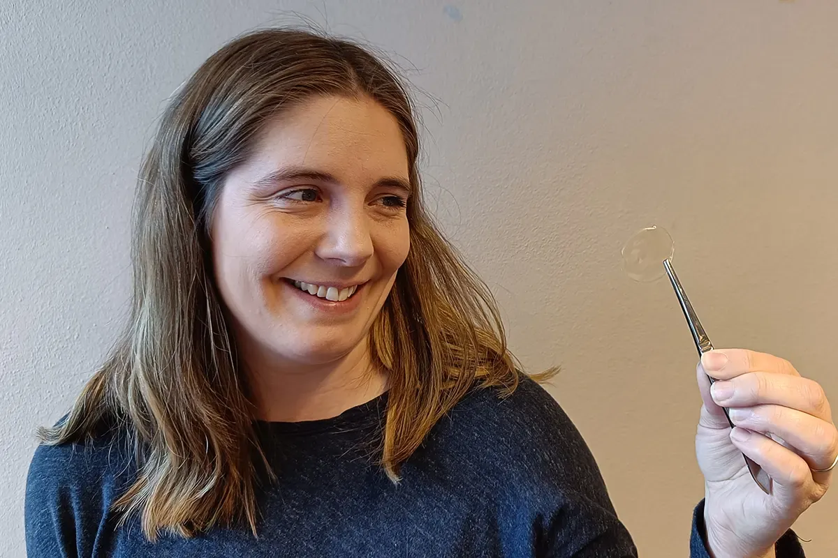 Helene Liepelt Nystedt held opp med pinsett ein gjennomsiktig og knapt synleg filmbit