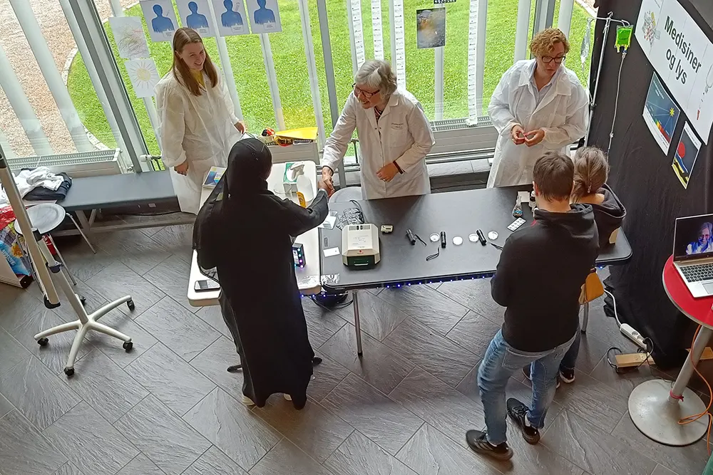 Standedn sett skrått ovanfrå. Besøk av to barn og ei kvinne i hijab