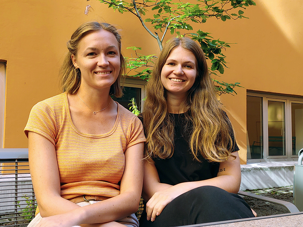 Kristine Horgen og Karoline Sandbakken sit på ein benk i bakgården på Farmasøytisk institutt