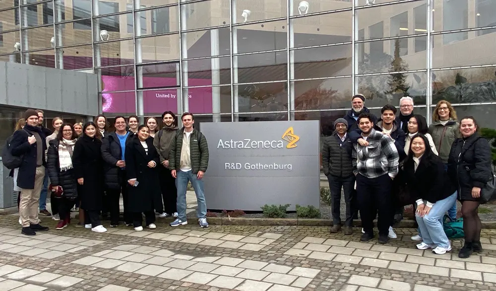 Gruppefoto av ca. 20 personar oppstilt rundt logoen til AstraZeneca