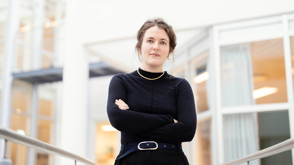 Kvinne i sort med kontorlokaler i bakgrunnen.