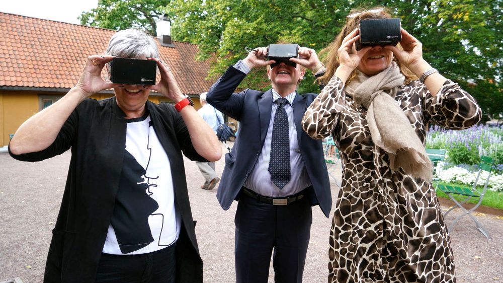 Three people facing the camera, looking into cheap 3D-glasses and smiling.