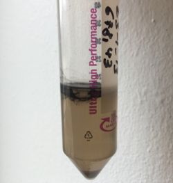 Photo of a sample of organic matter thriving on heavy liquid (ZnCl2) solution, below on the bottom is the inorganic mineral component, which did not dissolve during the acid treatment.  