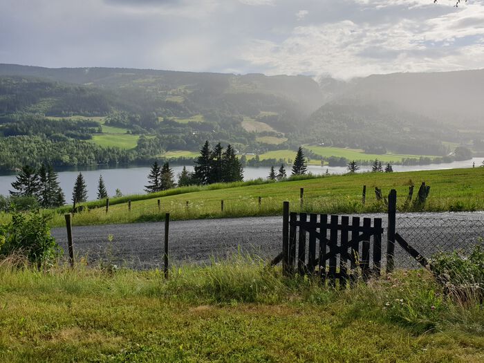 Regn over landbruksområde i Valdres. 