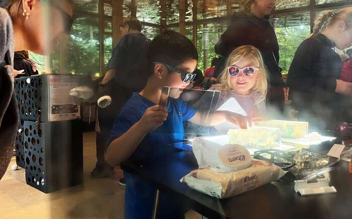 Two young visitors explore how stress propagates through a semi-solid material (gel). Placed on a light table and viewed through a filter, the gel reveals internal stresses when touched. Researcher Fabian Barras led this workshop. Photo: Jian Xu/UiO