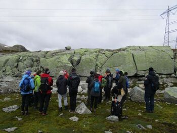 Studentene studerer steinblokker på området ved Jomfrunut, Finse. Grunnfjellet forvitrer og steinmassen sprekker langsomt opp.