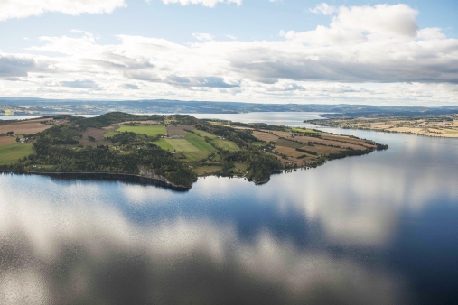 Mjøsa er Norges største innsjø og ligger i Akershus, Oppland og Hedmark. Her sees Helgøya, den største øya i Mjøsa, og den største i et innlandsvann i Norge. Den kambrosiluriske berggrunnen i Mjøsområdet er foldet i små og store folder og danner det karakteristiske bølgede vakre landskapet. Foto: Gunnar Klingwall (2014)