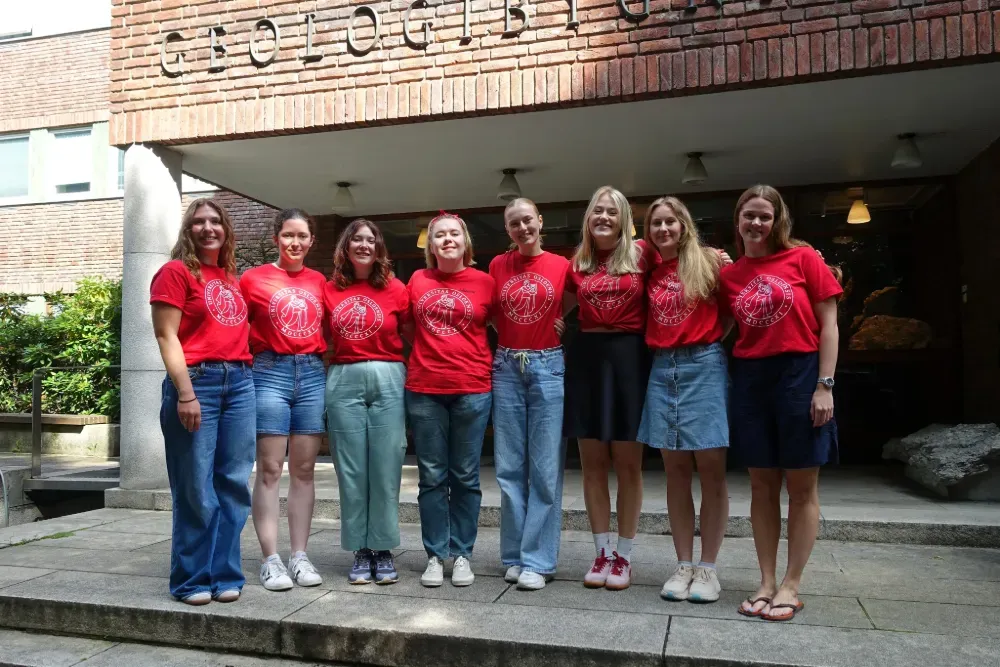 Eight women wearing red T-shirts standing side by side a line, serving as buddies for the upcoming buddy week