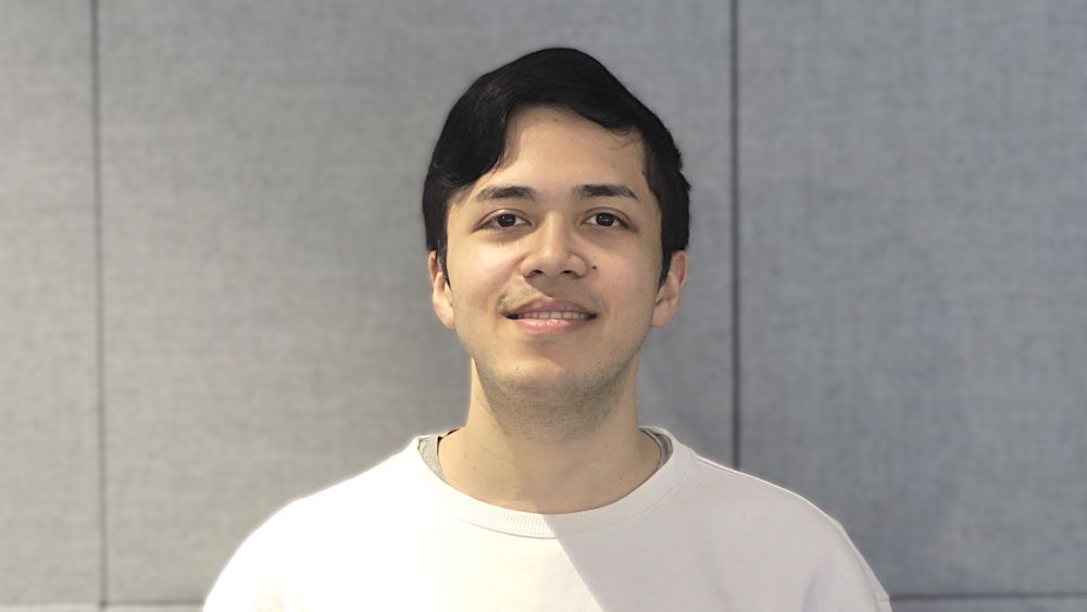 Young man with dark hair and fair skin wearing a white sweatshirt. 