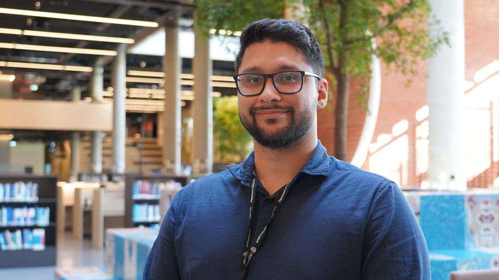 Portrait photo of Felipe Sousa Silva Adenilson in blue shirt in sunlight library. 