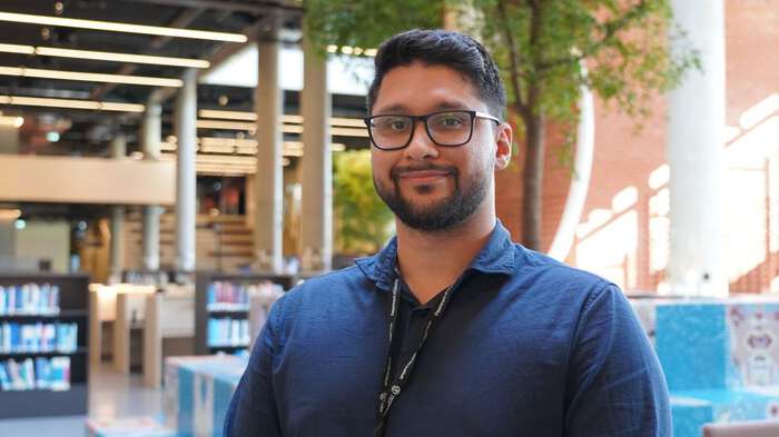 Portrait photo of Felipe Sousa Silva Adenilson in blue shirt in sunlight library. 