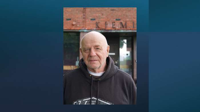 Man in his 70-ies with a big smile and wearing a dark sweather. 