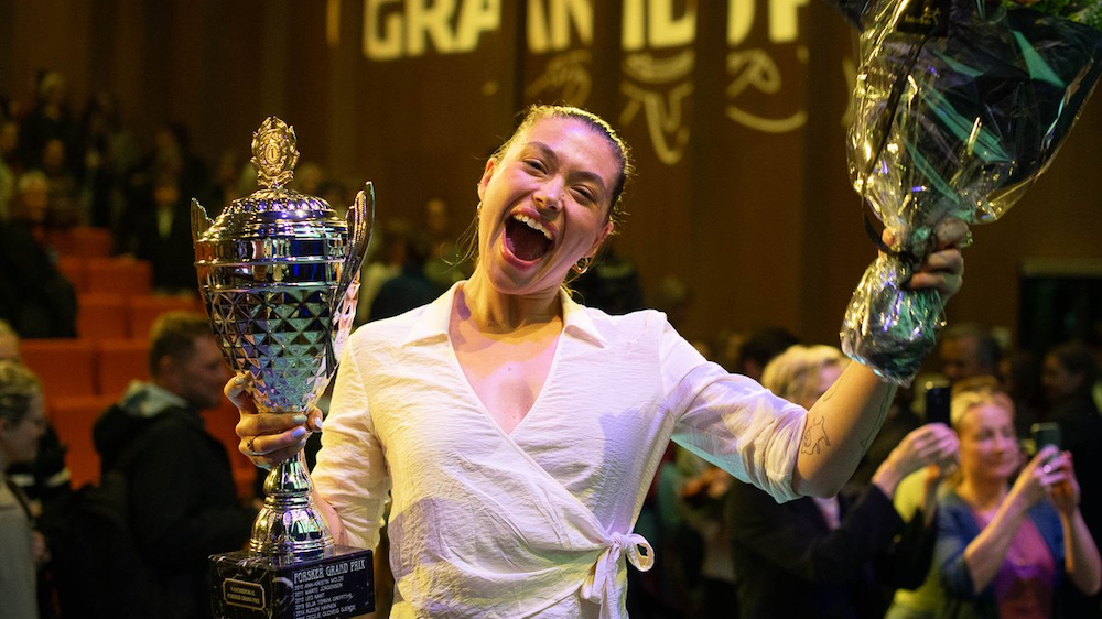Glad kvinne med pokal og blomster