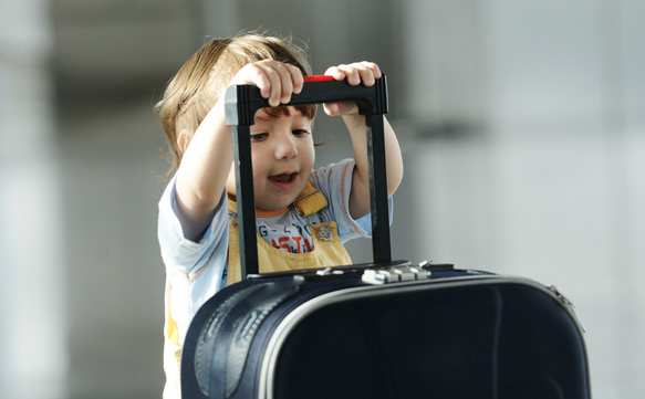 bildet viser et barn som holder på en stor koffert