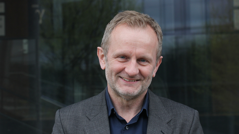 Portrettbilde av Egil Øvrelid foran informatikkbygget