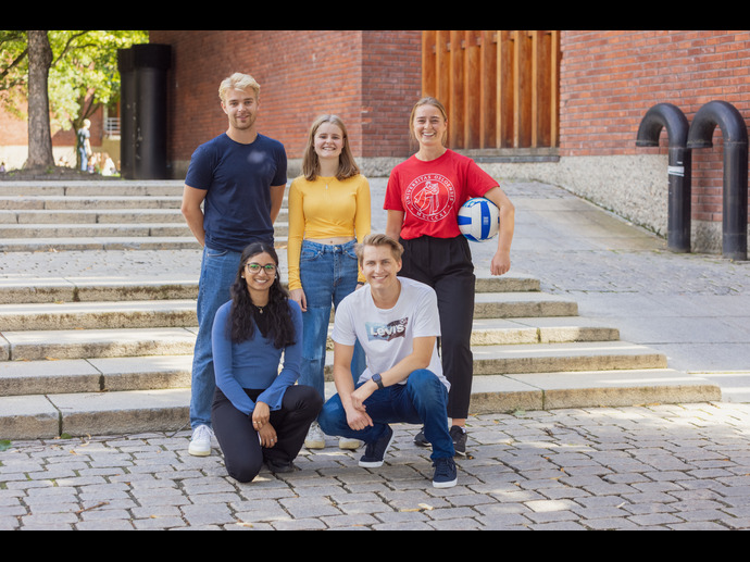 unge smilende kvinnelige og mannelige studenter ved trapp studiestart