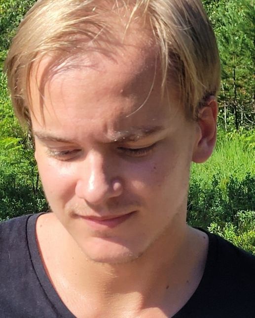 Portrait photo of Harald Fredriksen Høiland. He is wearing a blue T-shirt and has blond short hair. air, pail skin. 