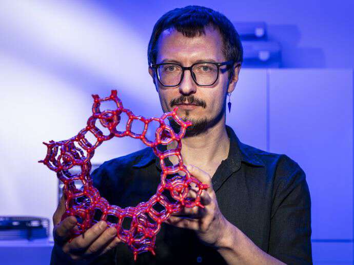 One male chemist showing a model of a molecyle.