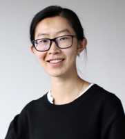Image may contain: A woman (Xinwei) is looking straight at the camera and smiling. She is wearing framed glasses and a black sweater. She is standing against a grey background. 