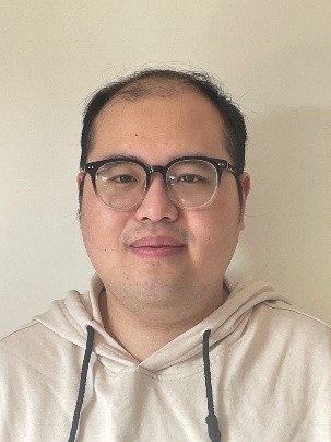 Image may contain: A person (Ning) looking straight at the camera. They have short black hair and are wearing a bright beige hoodie and glasses.