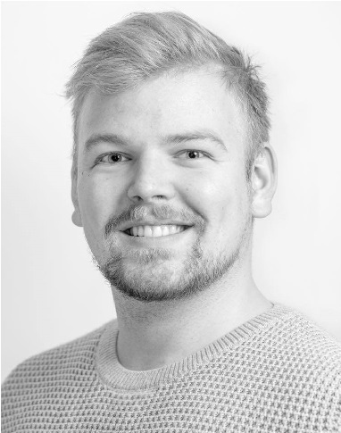 Image may contain: A person (Stian) is smiling and looking straight at the camera. They have short hair and are wearing a crocheted sweater.