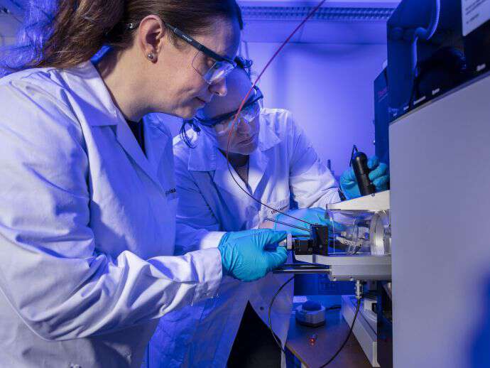 Hanne Røberg-Larsen og Kristina Sæterdal Kømurcu forsker blant annet på lab-on-a-chip-teknologi. Her på bildet er begge med labfrakk og annet nødvendig verneutstyr å gjøre kjemiske analyser.