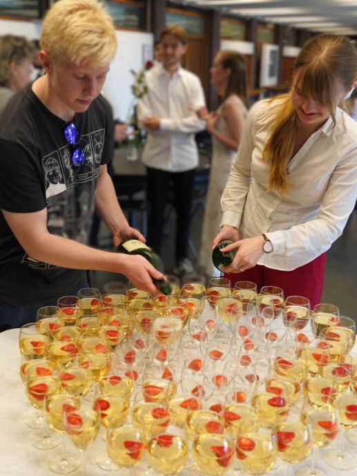 To unge studenter serverer i jordbær og brus i glass. 