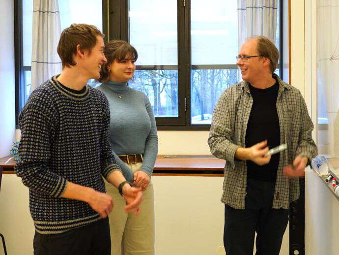 To studenter i tett dialog med forsker og underviser.