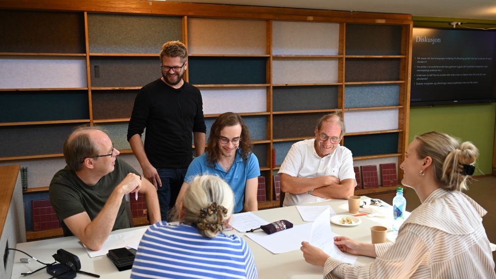mann som snakker med gruppe rundt et bord