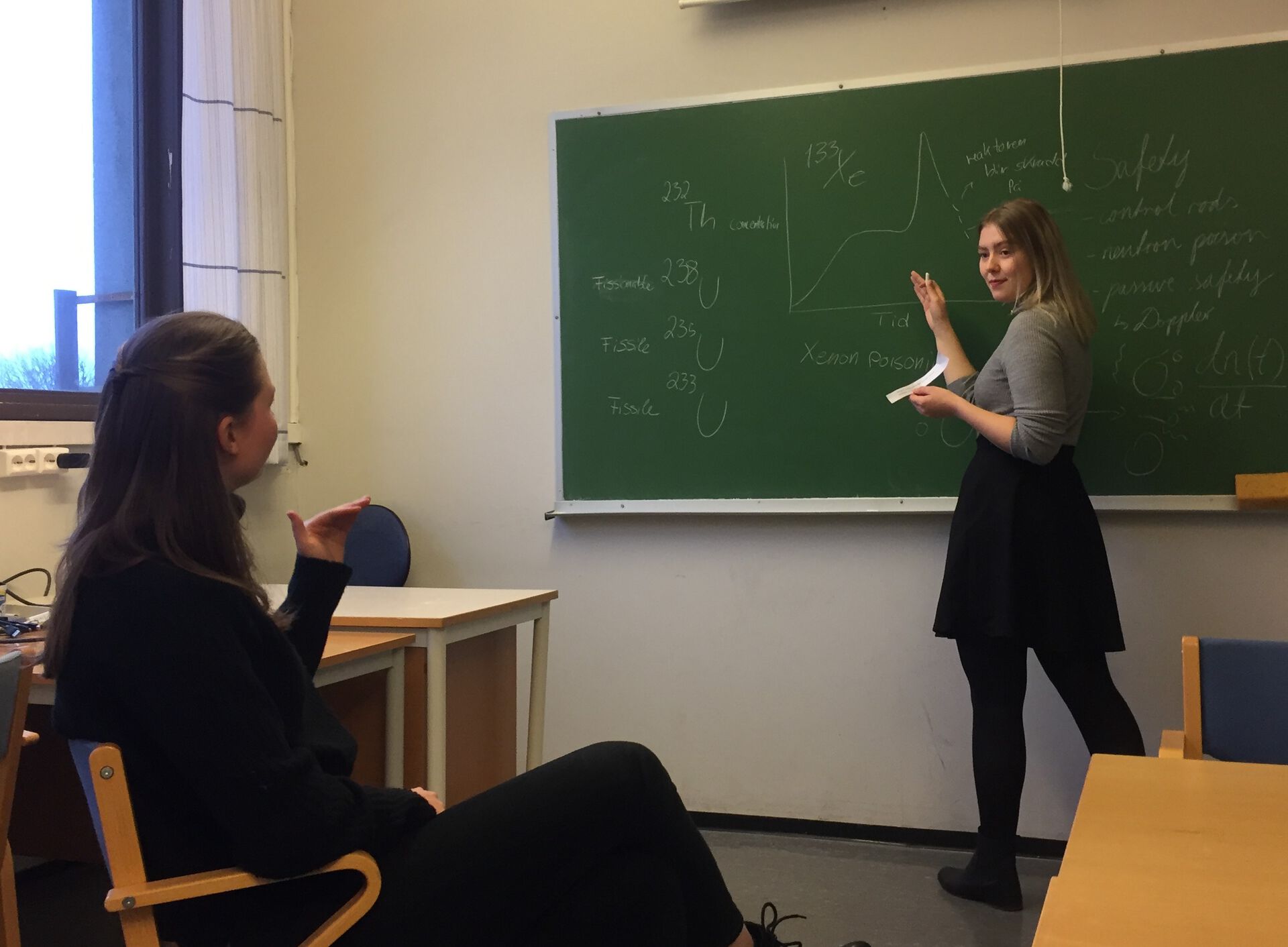 Student stiller spørsmål til medstudent ved tavl.