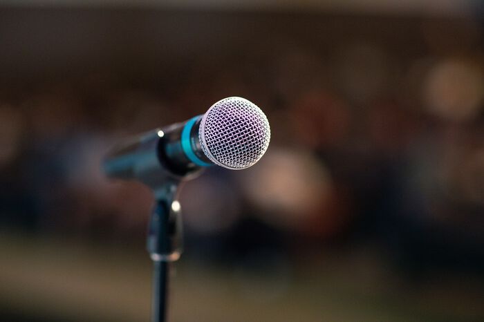Illustrasjonsbilde av mikrofon i et lokale med publikum